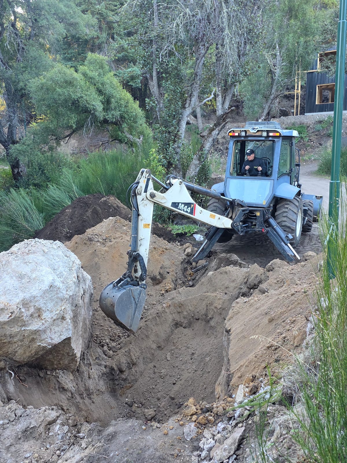 Retroexcavadora de Salvagno trabajando junto a una gran piedra en la cordillera